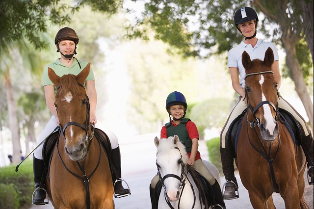 2 adult riders accompanying a younger rider in between on a ride