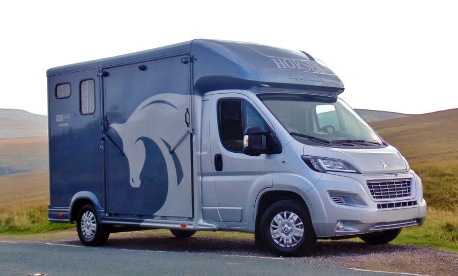 A blue horsebox parked at the side of the road