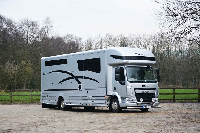 A silver horsebox in a yard